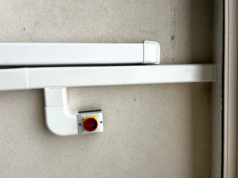 Goulottes blanches et interrupteur de proximité le long d'un mur extérieur