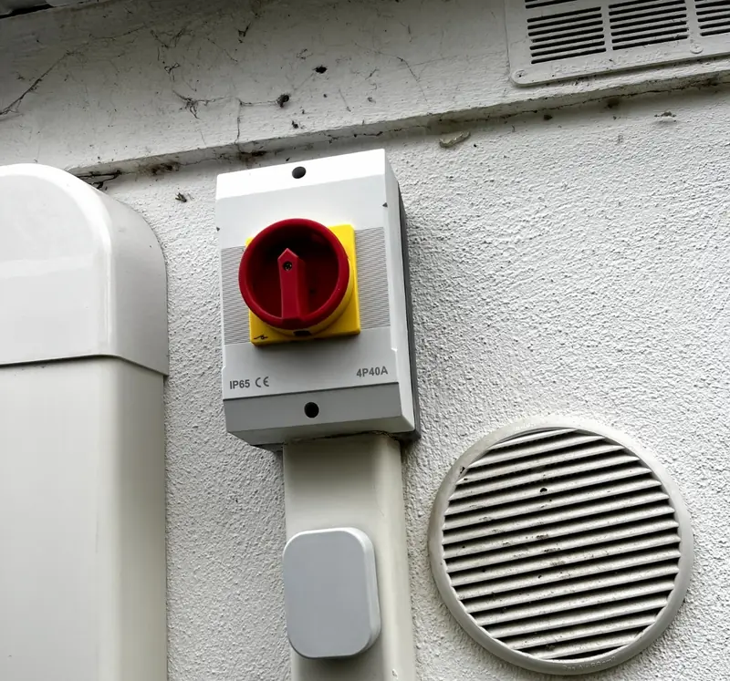 Interrupteur de proximité rouge et jaune près de l'unité extérieure, câble sous goulotte