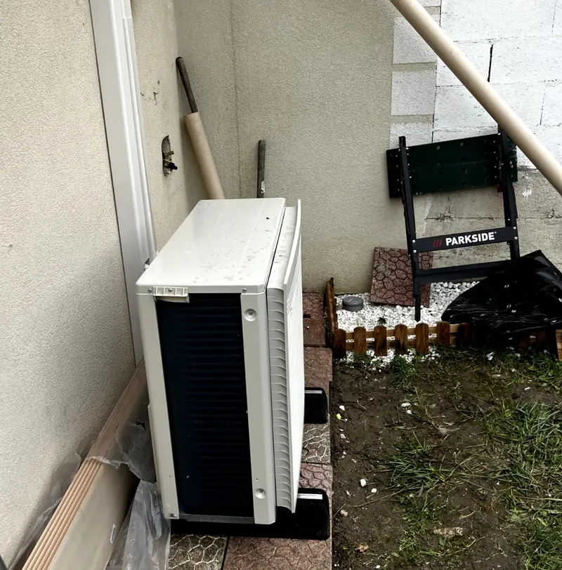Unité extérieure de pompe à chaleur air/air posée au sol dans un jardin